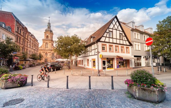 02 August 2019, Saarbrucken, Germany: View of the old town in the historic centre of Saarbrücken, with cyclists passing along the street