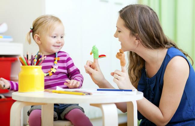 Young mother and her toddler girl playing together with finger toys