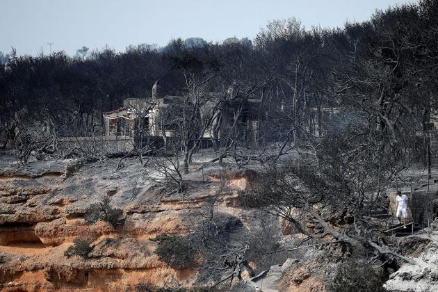 A local walks on a burnt slope following a wildfire at the village of Mati, near Athens, Greece, July 24, 2018. REUTERS/Alkis Konstantinidis - RC1A88812700