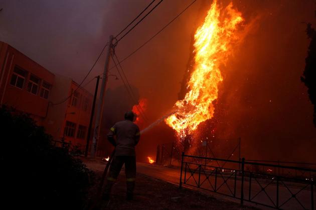 A firefighter tries to extinguish a wildfire burning in the town of Rafina, near Athens, Greece, July 23, 2018. REUTERS/Costas Baltas - RC187936FE10