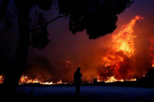 A man looks at the flames as a wildfire burns in the town of Rafina, near Athens, Greece, July 23, 2018. REUTERS/Costas Baltas TPX IMAGES OF THE DAY - RC142304D660