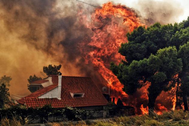TOPSHOT - A house is threatened by a huge blaze during a wildfire in Kineta, near Athens, on July 23, 2018. - More than 300 firefighters, five aircraft and two helicopters have been mobilised to tackle the "extremely difficult" situation due to strong gus
