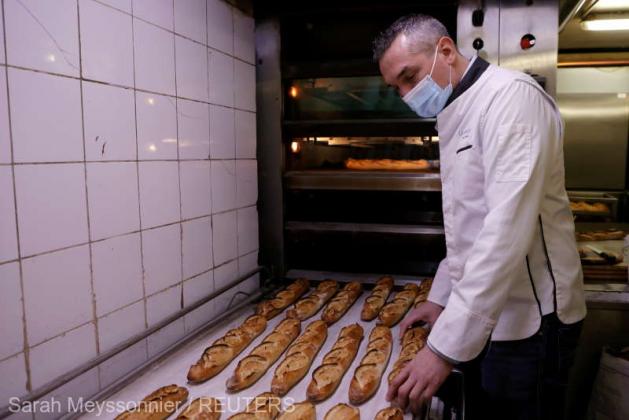 French baker Mickael Reydellet, wearing a protective face mask, looks a tray of freshly-baked baguettes near the oven at "La Parisienne" bakery in Paris, France, February 17, 2021. Picture taken on February 17, 2021. REUTERS/Sarah Meyssonnier