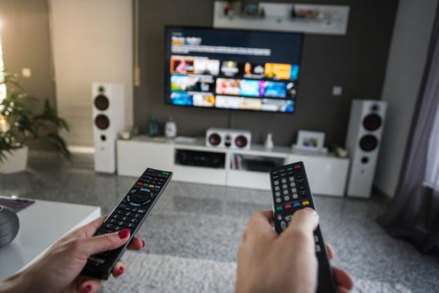Man and woman with television remote control - stock photo