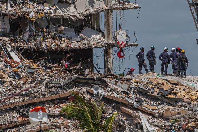 (FILES) In this file photo Search and Rescue teams look for possible survivors in the partially collapsed 12-story Champlain Towers South condo building on June 27, 2021 in Surfside, Florida. US President Joe Biden said on June 29, 2021 he hoped to visit 