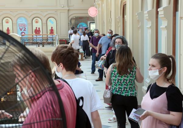 6581524 24.06.2021 People wearing protective face masks wait to receive a dose of Russian Gam-COVID-VAK (trademark "Sputnik V") coronavirus vaccine outside a vaccination point at the GUM State Department Store amid the coronavirus pandemic, in Moscow, Rus