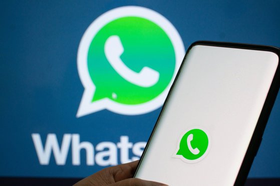 Jaipur, India, Circa 2020 - A mobile logged into the whatsapp mobile application infront of the white light board with whatsapp logo on it. The background board is brightly lit. The screen shows the mobile application logging in.,Image: 573159621, License