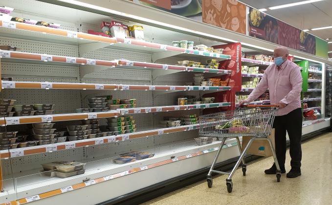 A shopper wearing a face covering looks at nearly empty shelves of pre-cooked meat products in Sainsbury's, north London just after 9am. The Government and retailers warn that food and fuel shortages could continue until Christmas due to labour shortages 